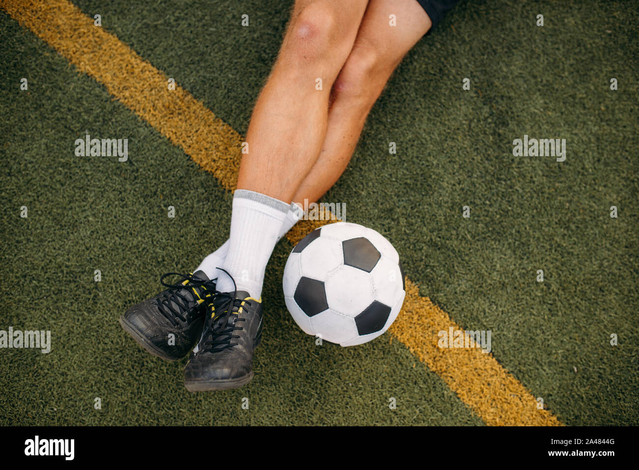 Männliche Fußballspieler mit Ball auf dem Rasen sitzen Stockfoto