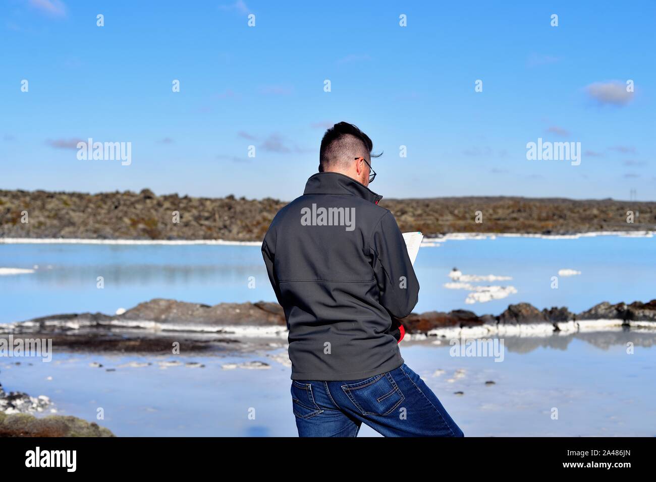 Svartsengi, Island. Eine touristische berät einen Reiseführer, während auf den Felsen rund um die Blaue Lagune Island ist eine der wichtigsten touristischen Attraktionen. Stockfoto