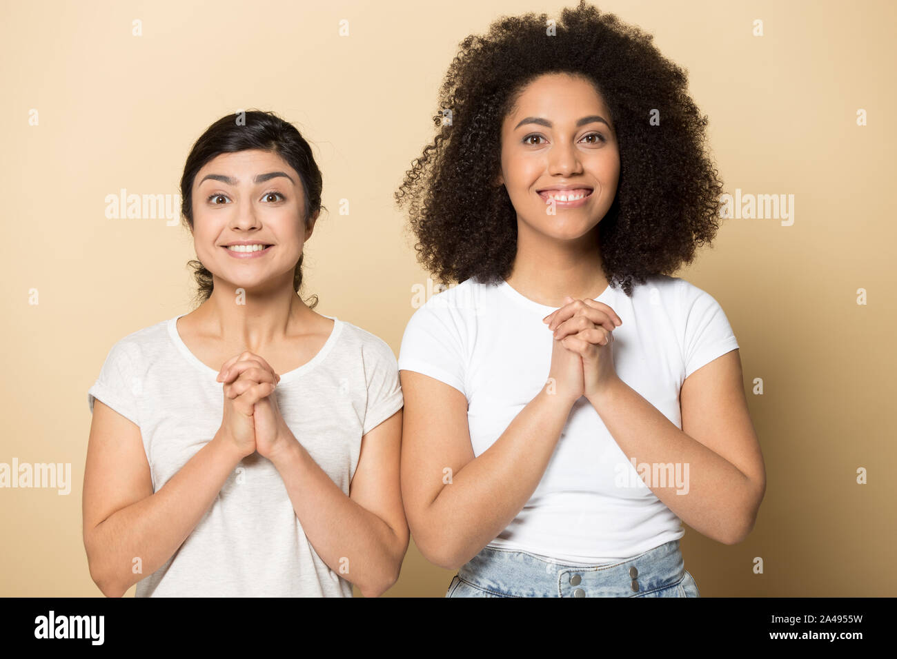 Lächelnd internationale Freundinnen mit Hände im Gebet Hoffnung für beste Stockfoto