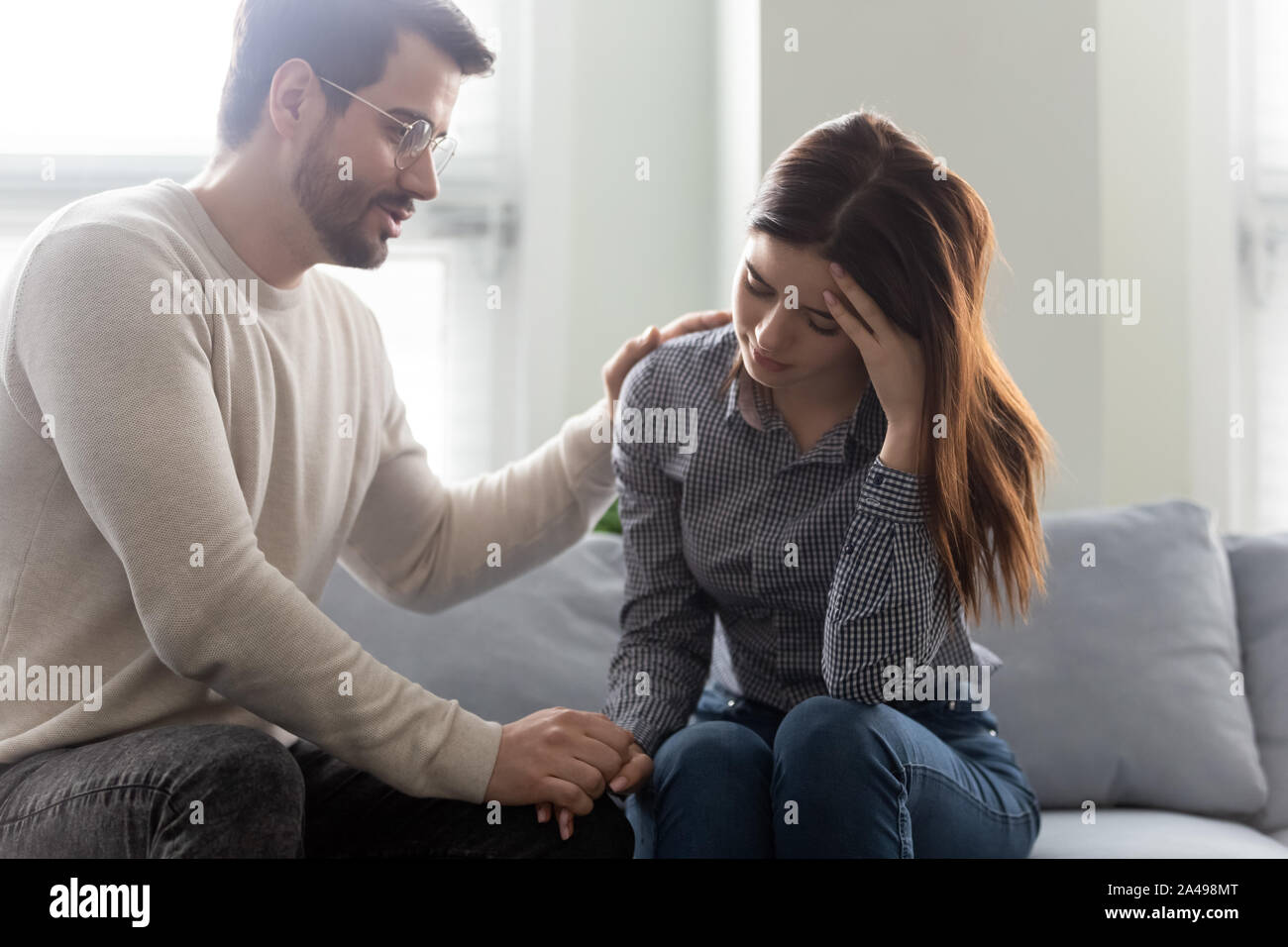 Unglücklich betonte Frau sitzt auf einem Sofa mit einfühlsamen Mann. Stockfoto