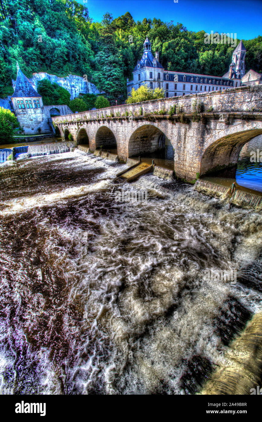 Brantome en Périgord, Frankreich. Der Pont Coude (rechter Winkel Brücke) über den Fluss Dronne, mit der Abtei von Brantome im Hintergrund. Stockfoto