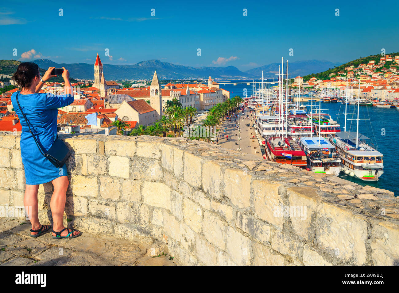 Reisende Frau, ein Foto mit Telefon aus der Burg. Ziemlich touristische Frau mit Smartphone, die Bilder in der Altstadt von Trogir, Dalmatien, C Stockfoto