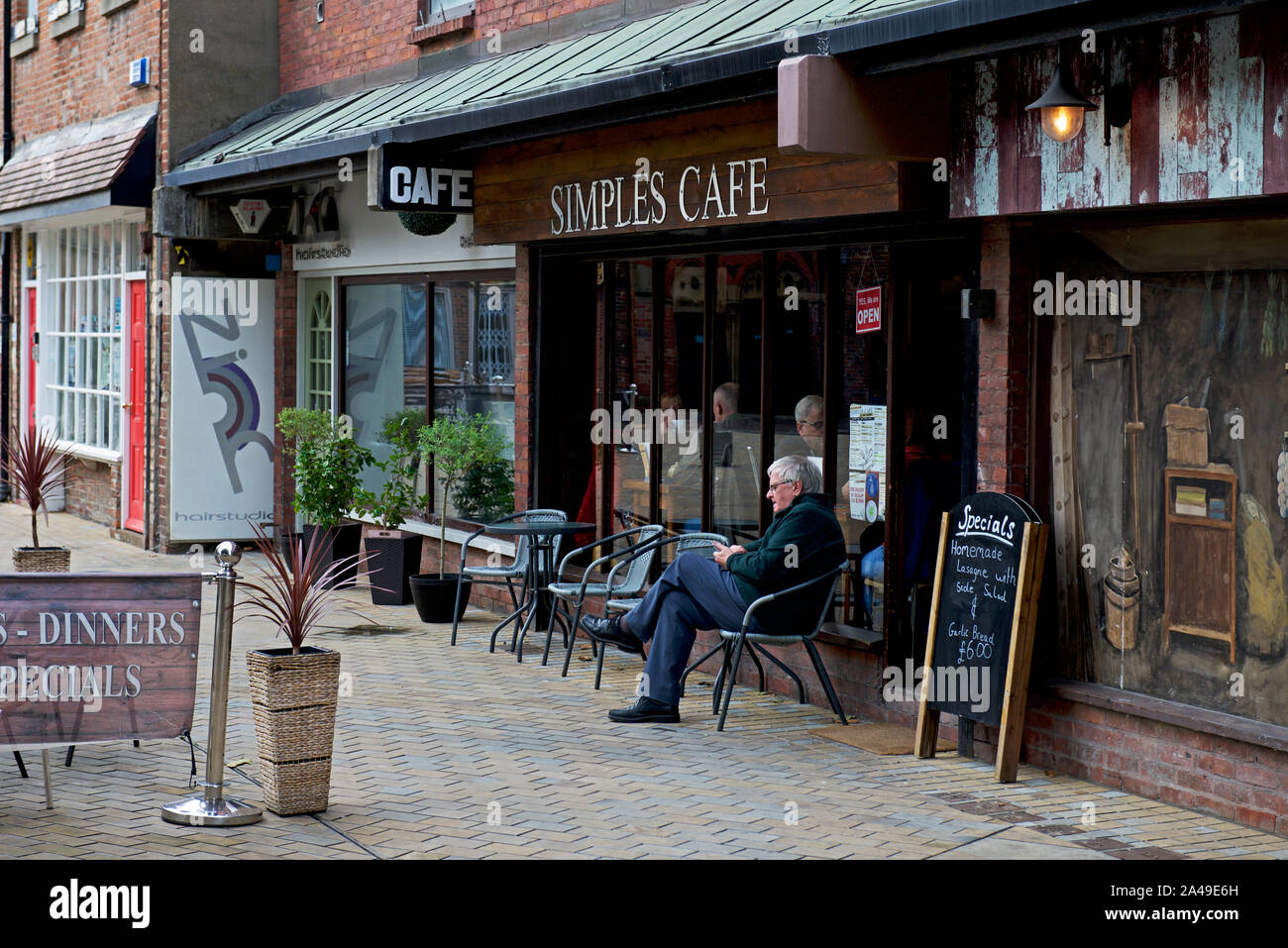 Mann außerhalb Simples Café, Trinity Square, Kingston upon Hull, East Yorkshire, England UK sitzen Stockfoto