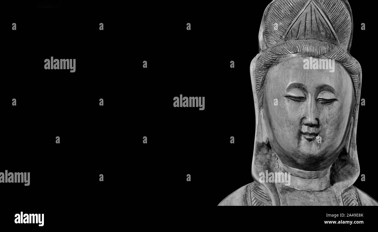 Buddhistische Religion und Meditation. Kannon der Guanyin, der Göttin der Barmherzigkeit, Holz- statuette auf schwarzem Hintergrund (Schwarz und Weiß mit Kopie Raum) Stockfoto