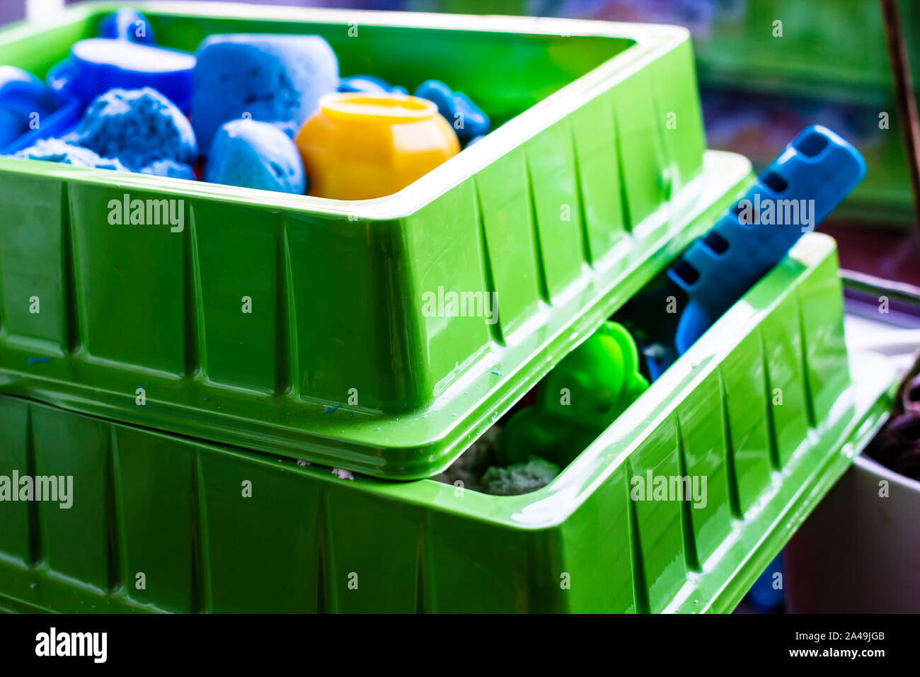 Zwei Container mit kinetischen Sand und Kunststoff Spielzeug für die Entwicklung der Feinmotorik und Kreativität bei Kindern. Close-up. Stockfoto