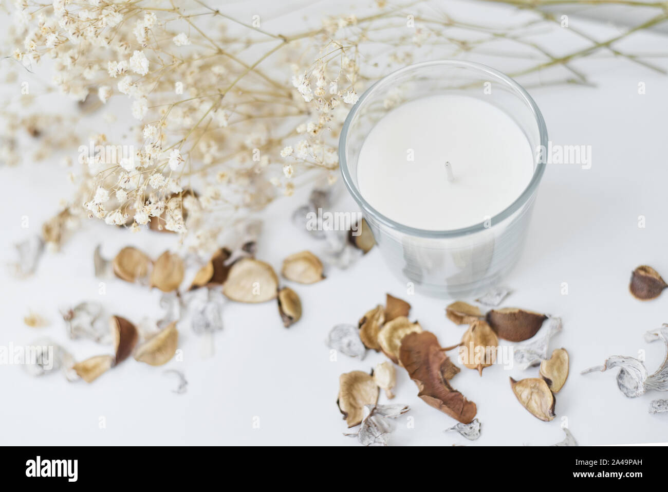 Kerze mit floralem Dekor auf weißer Tisch. Gemütlich und hygge Hintergrund Stockfoto