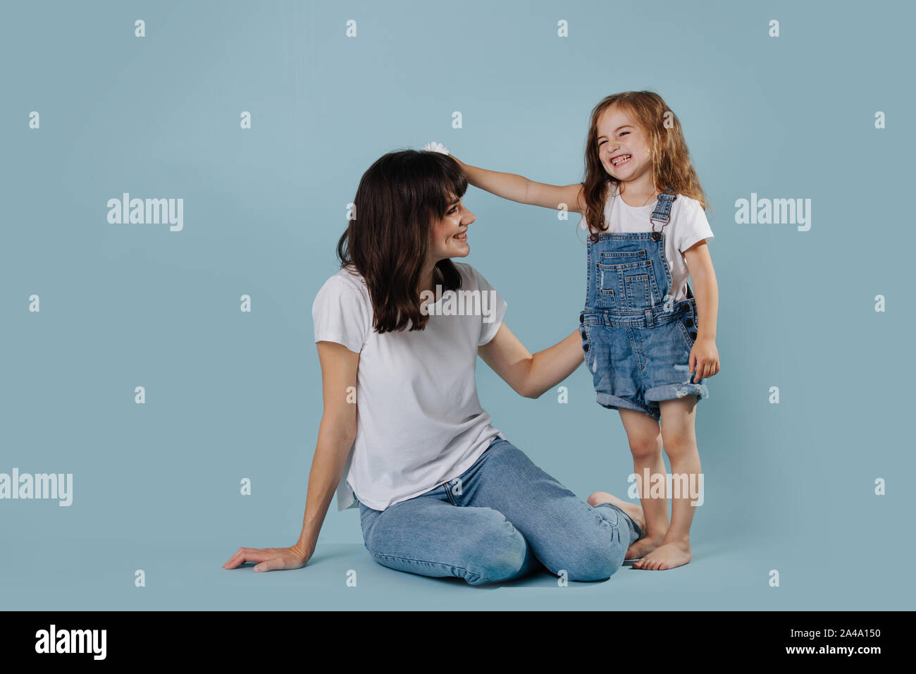 Mutter und Tochter Gekleidet in weiße T-Shirts und Jeans sind lächelnd Stockfoto
