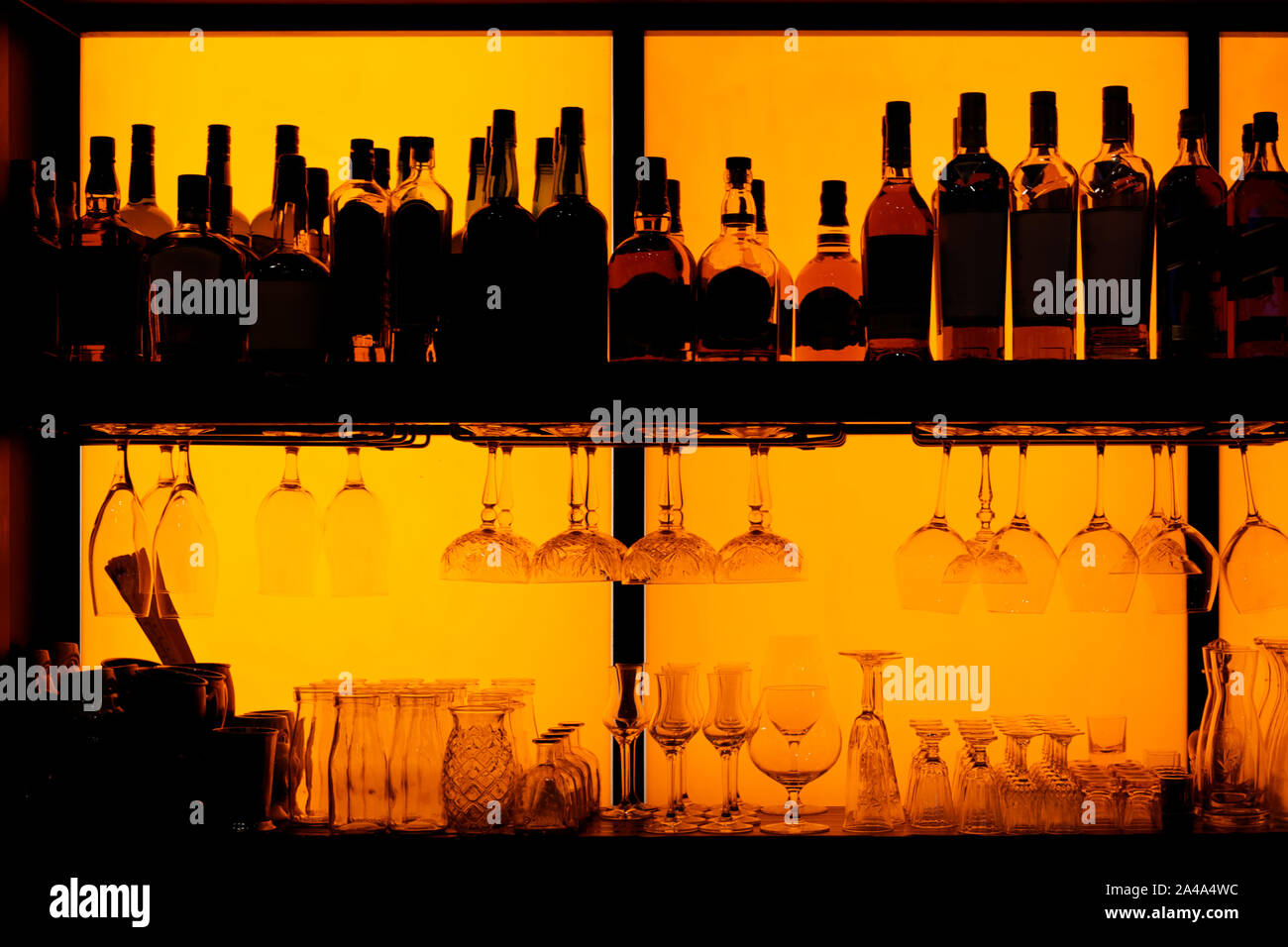 Flaschen und Gläser auf dem Regal sitzen in einer Bar, beleuchtete, Markennamen entfernt Stockfoto