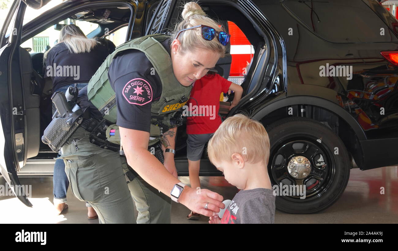 Eine Polizistin gibt ein kleiner Junge einen Aufkleber im Fire Station open house. Stockfoto