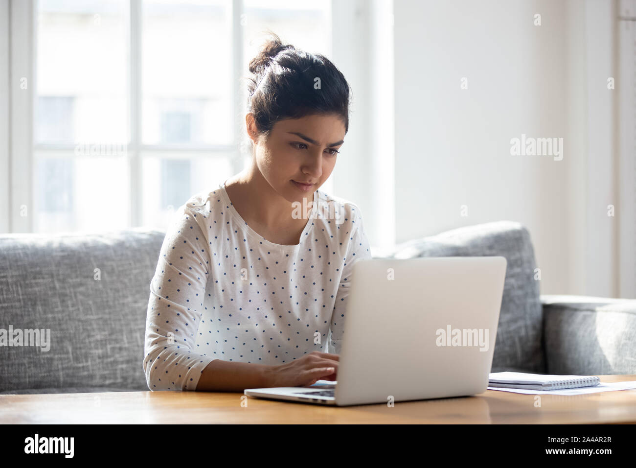 Indische Frau mit Laptop zuhause gelegt, auf Bildschirm Stockfoto