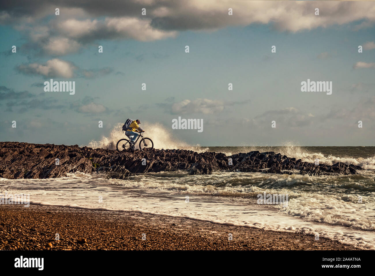 Radfahren in Irland. Freizeit Radfahrer mit Mountain Bike und Rucksack, die versuchen, auf dem Meer Felsen am Rande der wellige Meer zu fahren. Stockfoto