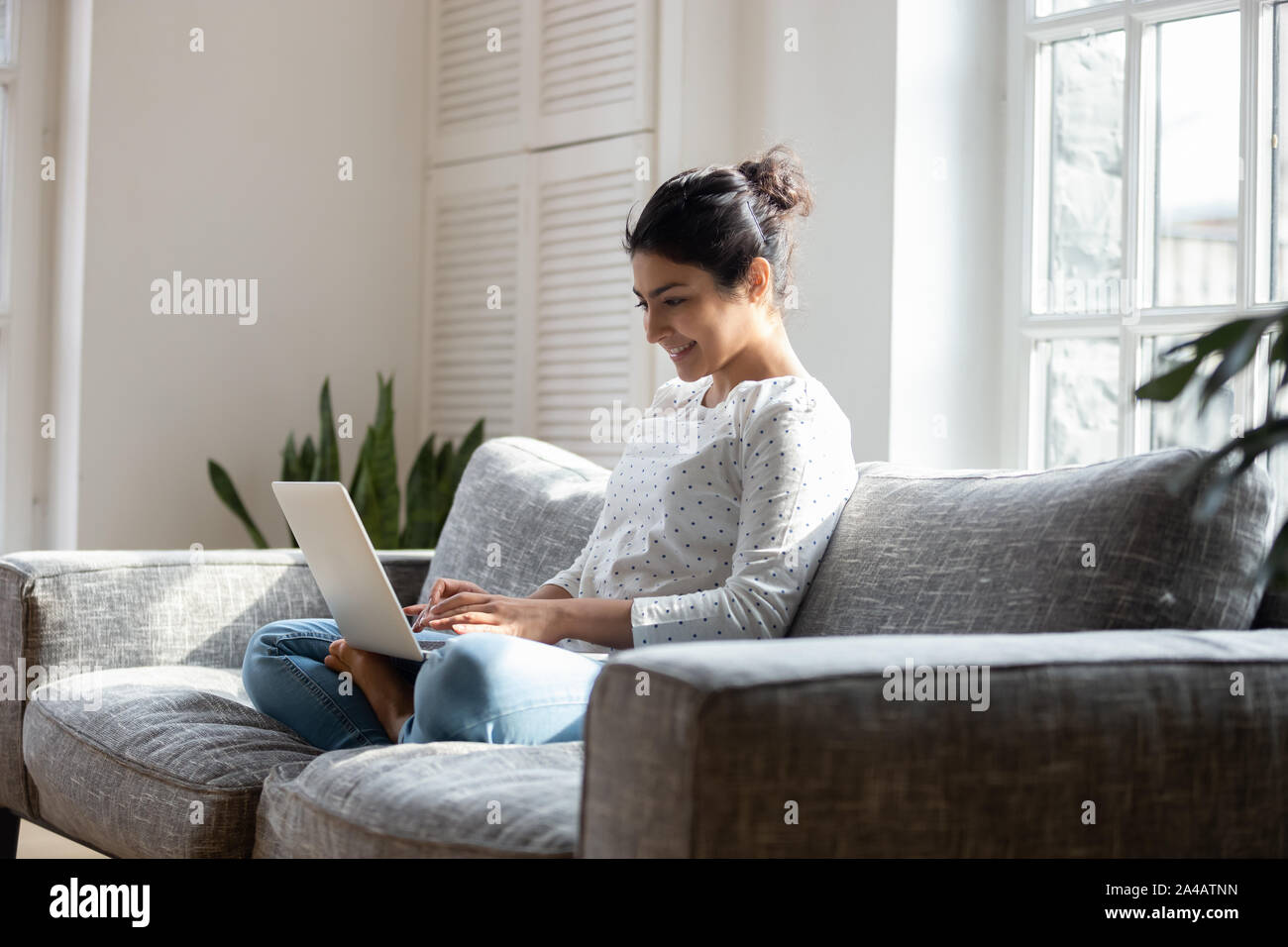 Zufrieden indische Frau entspannen auf der Couch, mit Laptop zu Hause Stockfoto