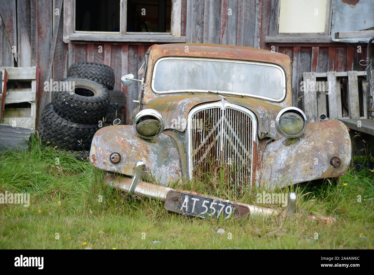 Ein verlassenes Auto liegt neben einer alten Scheune in Neuseeland Stockfoto