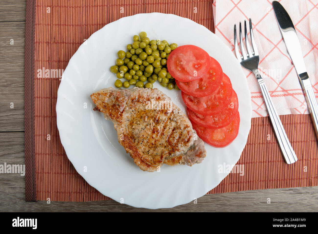 Gegrilltes Schweinefleisch Steak Fleisch mit Erbsen und Tomaten klein schneiden. Ansicht von oben Stockfoto