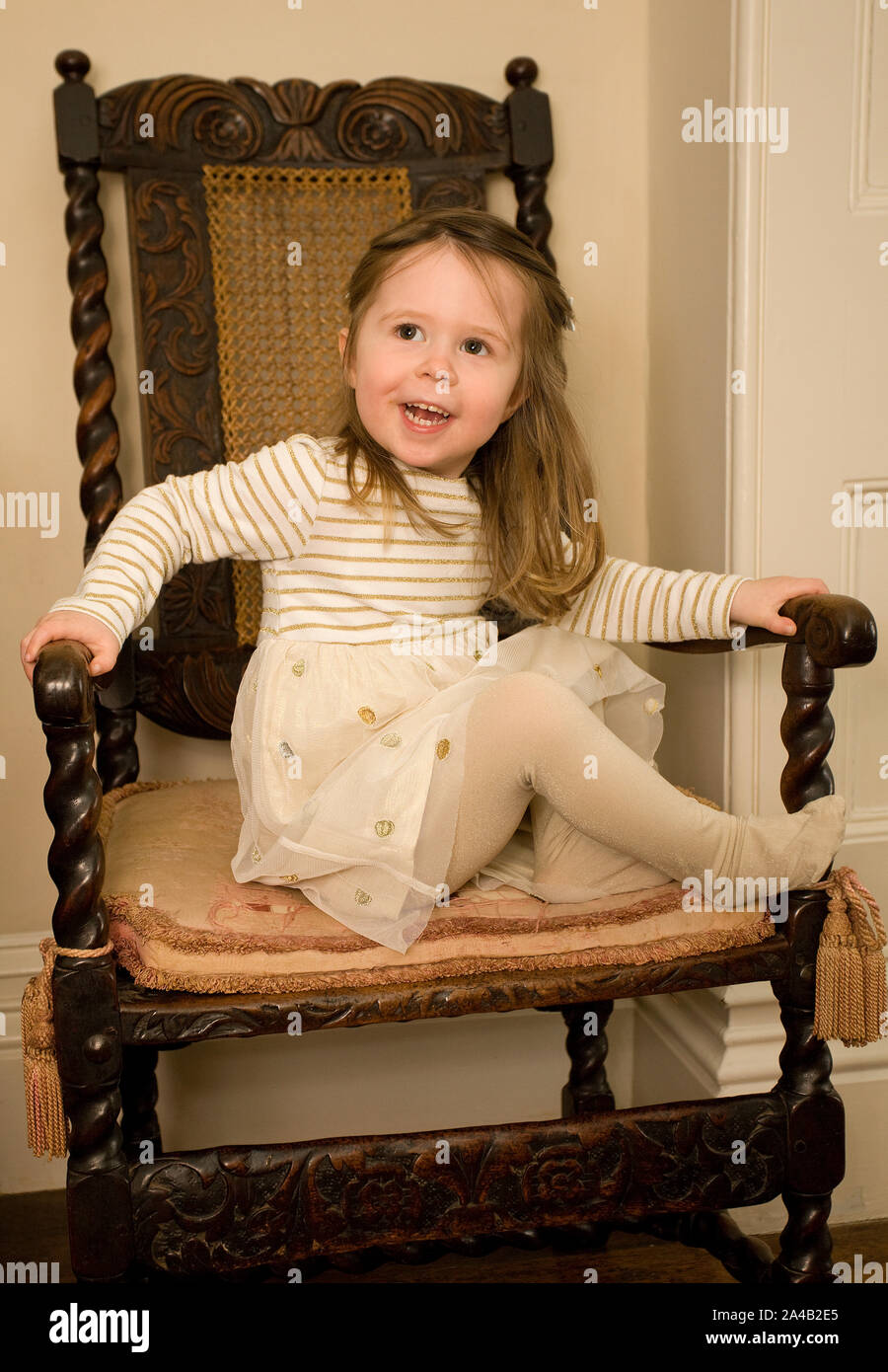 Weibliche Kleinkind saß auf Stuhl ihre Partei Kleid tragen Stockfoto