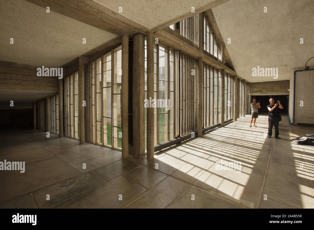 Besucher im Atrium der Kreuzgang des Klosters von Sainte Marie de la Tourette entworfen von Schweizer modernistischen Architekten Le Corbusier (1959) in Éveux in der Nähe von Lyon, Frankreich. Stockfoto