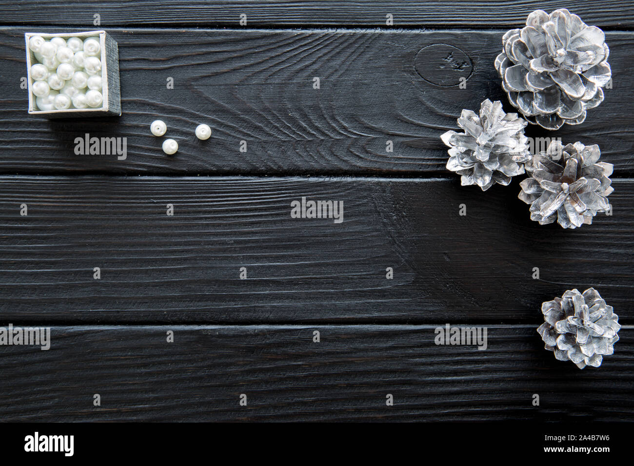 Silberne Tannenzapfen (Tannen Zapfen) und Silber mit weißen glitzernden Perlen auf schwarzen Holztisch Hintergrund. Platz für Text. Freier Speicherplatz für die Begrüßung. Cop Stockfoto