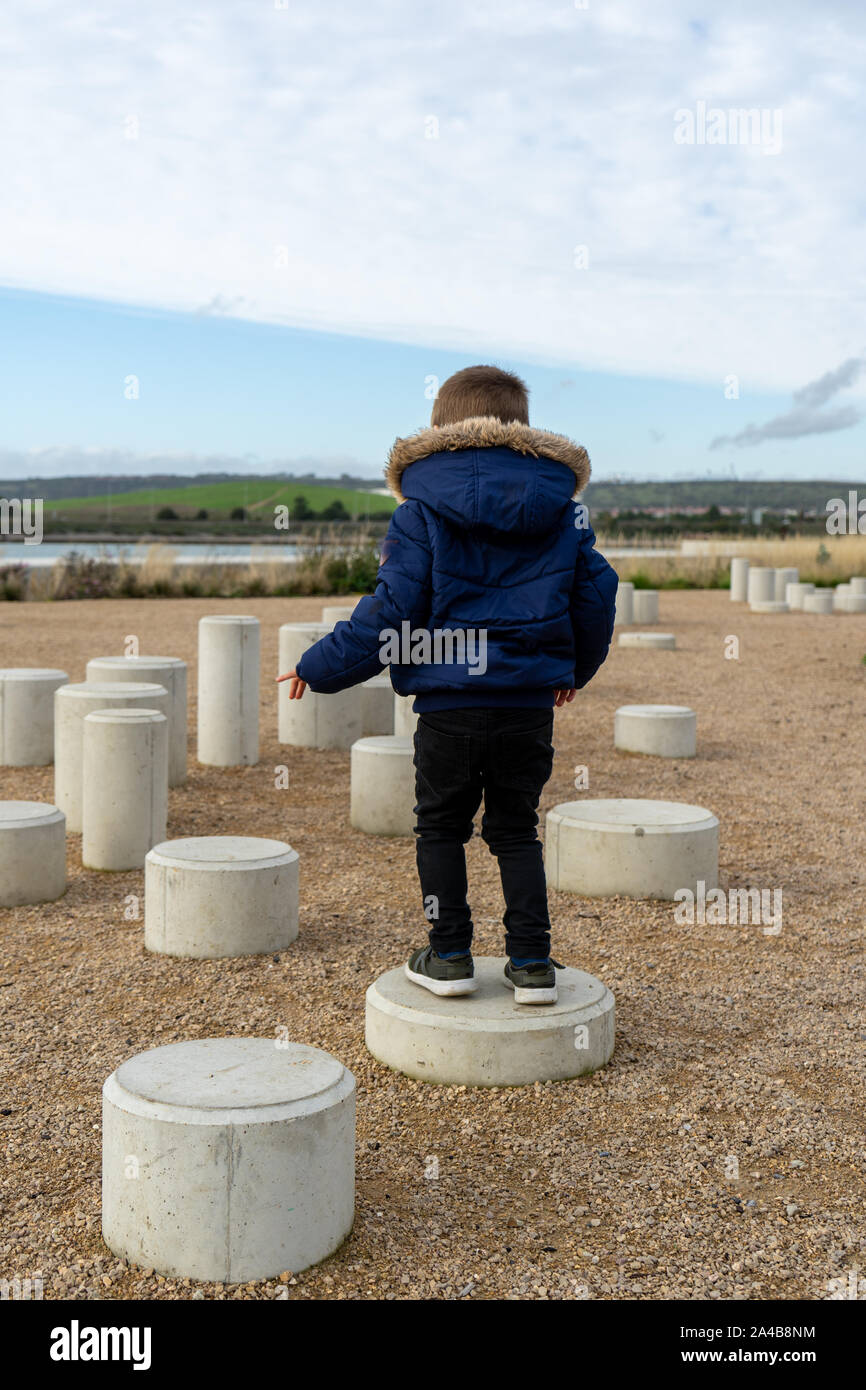 Ein kleiner Junge im Winter Kleidung stehen auf Stepping Stones Stockfoto