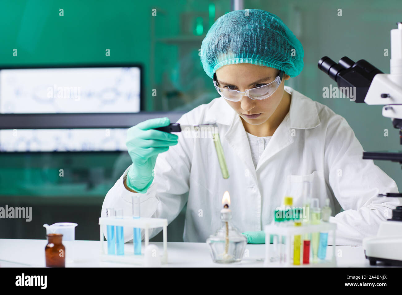 Porträt der jungen Frau mit Reagenzglas über Gasbrenner während der Arbeit an der wissenschaftlichen Forschung im Labor, in der Kopie Raum Stockfoto