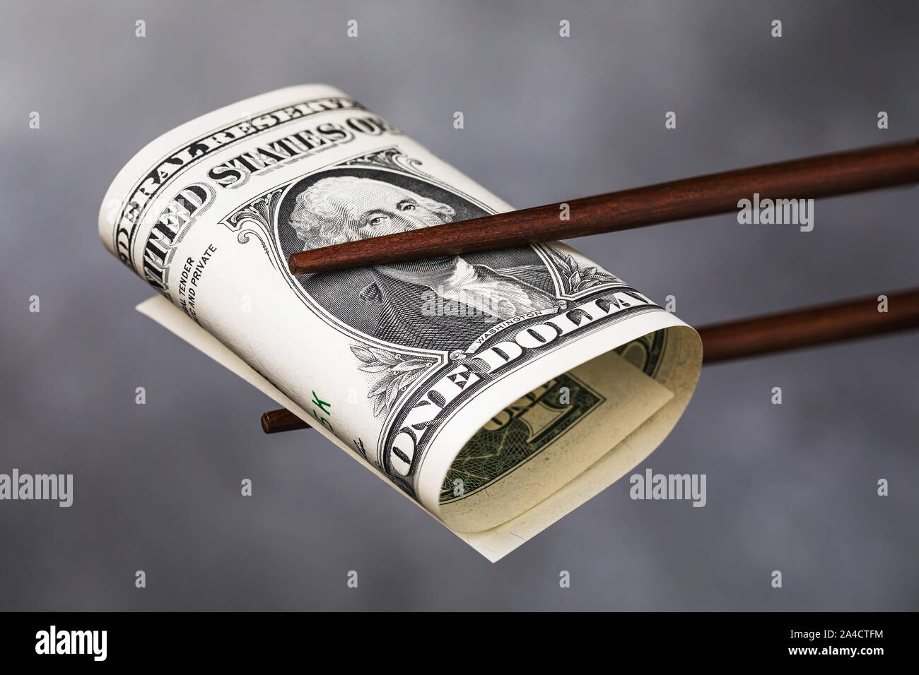 Chinesische Essstäbchen halten einen Dollar, Nahaufnahme. Ein Konzept, das auf die Beziehung zwischen Amerika und China Stockfoto