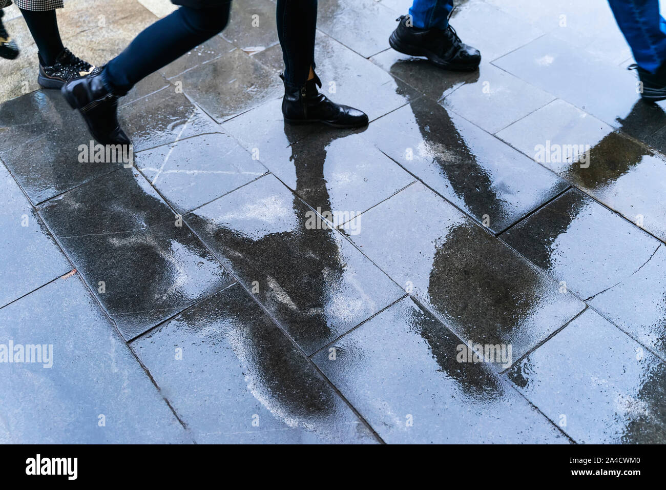 Unscharfe Reflexion Beine und Schatten, Silhouetten der Menschen in den nassen Bürgersteig, in eine Pfütze von Menschen zu Fuß auf einem Regen Stockfoto