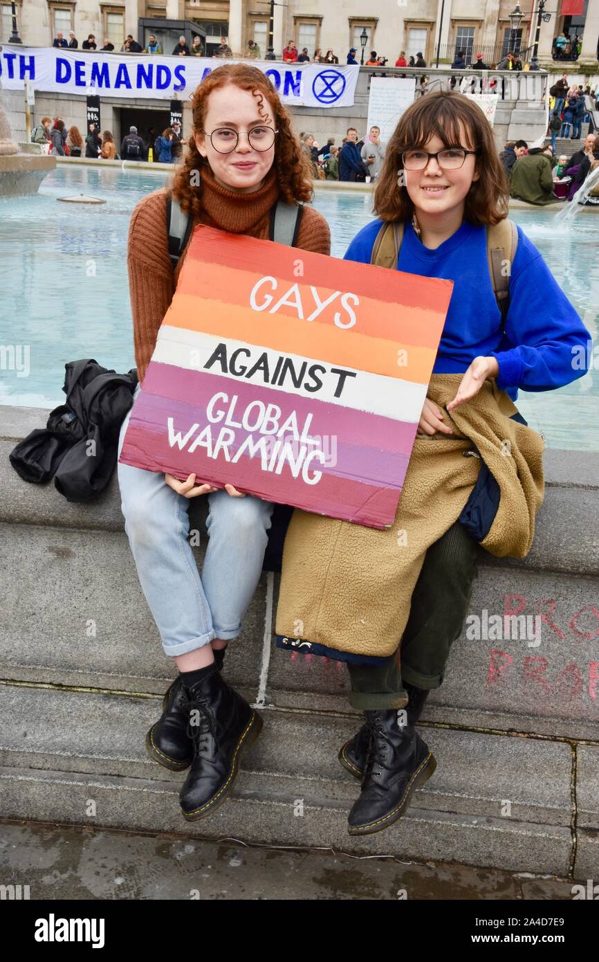 Die Demonstranten. Paar hält ein Plakat: "Gay ist gegen die globale Erwärmung", Aussterben Rebellion Protest, Tag 6, Trafalgar Square, London. Großbritannien Stockfoto