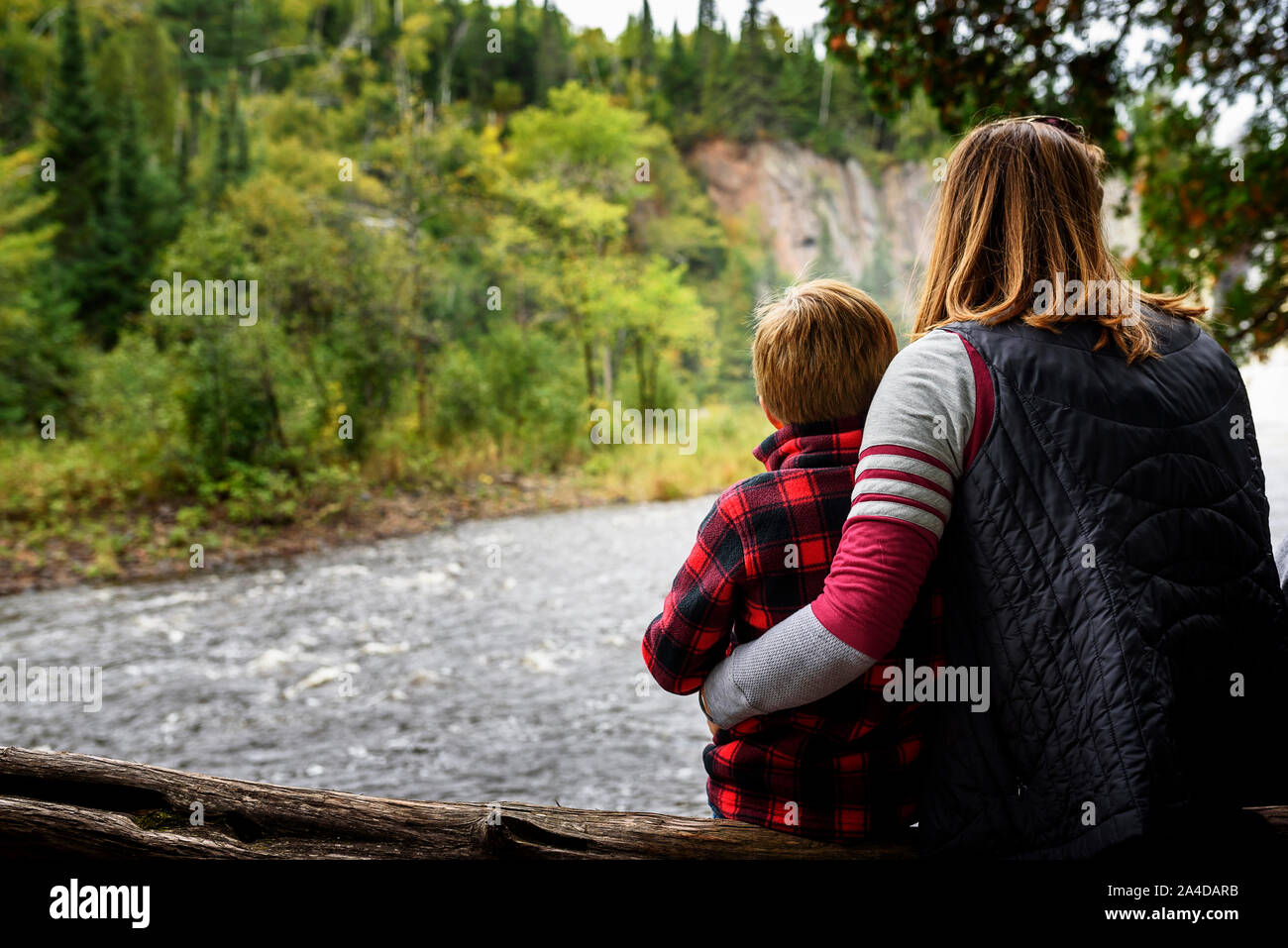 Mutter und Sohn sitzen auf einem Baumstamm in Aussicht suchen, United States Stockfoto