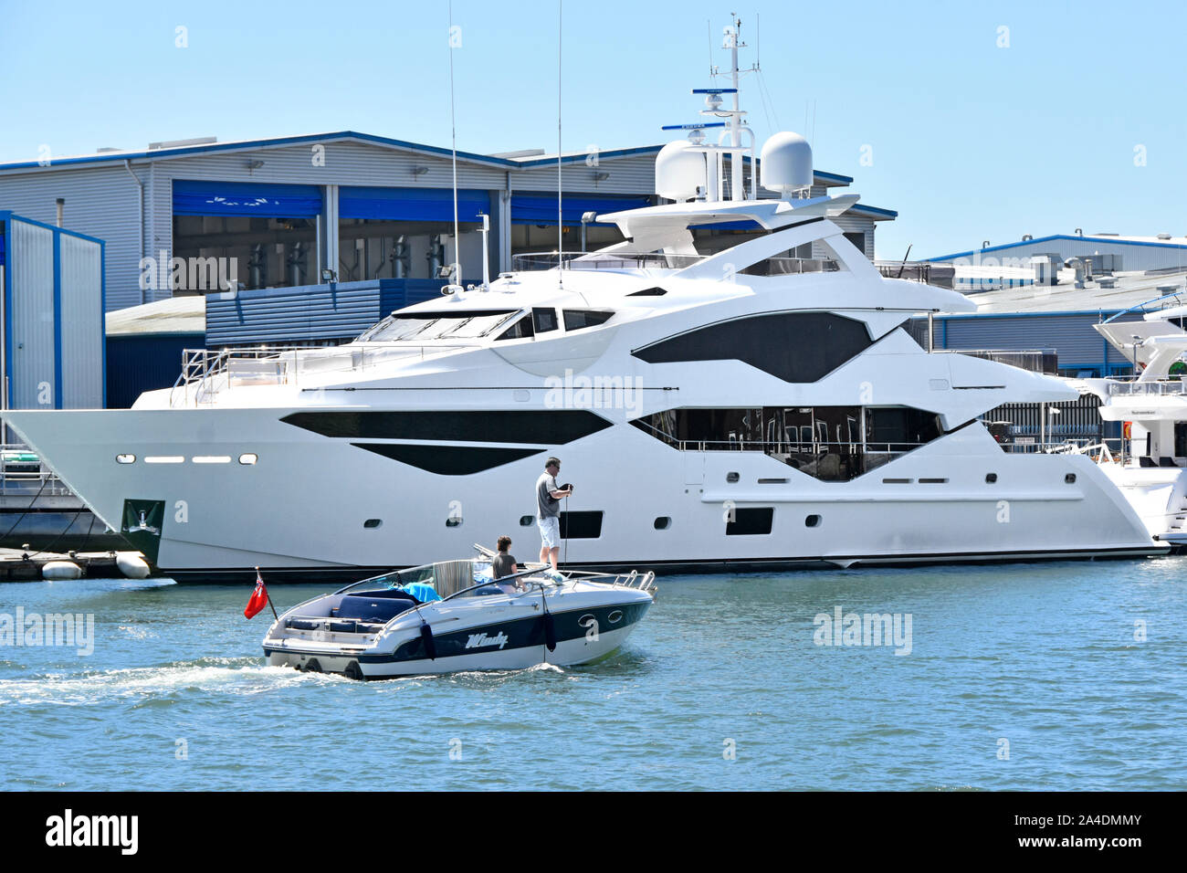 Menschen auf kleinen Motorboot vorbei günstig Luxus motor yacht von der Sunseeker Business in seinem Hof & Werk produziert in den Hafen von Poole Dorset UK Stockfoto