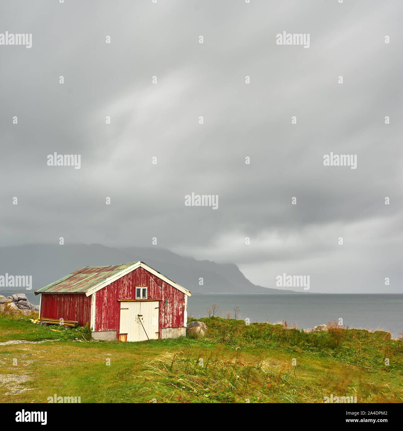 Diese rote Hütte steht auf der rauen Küste der Lofoten. Im Hintergrund starken Regen Wolken Regen bringt. schönes Szenario. Stockfoto