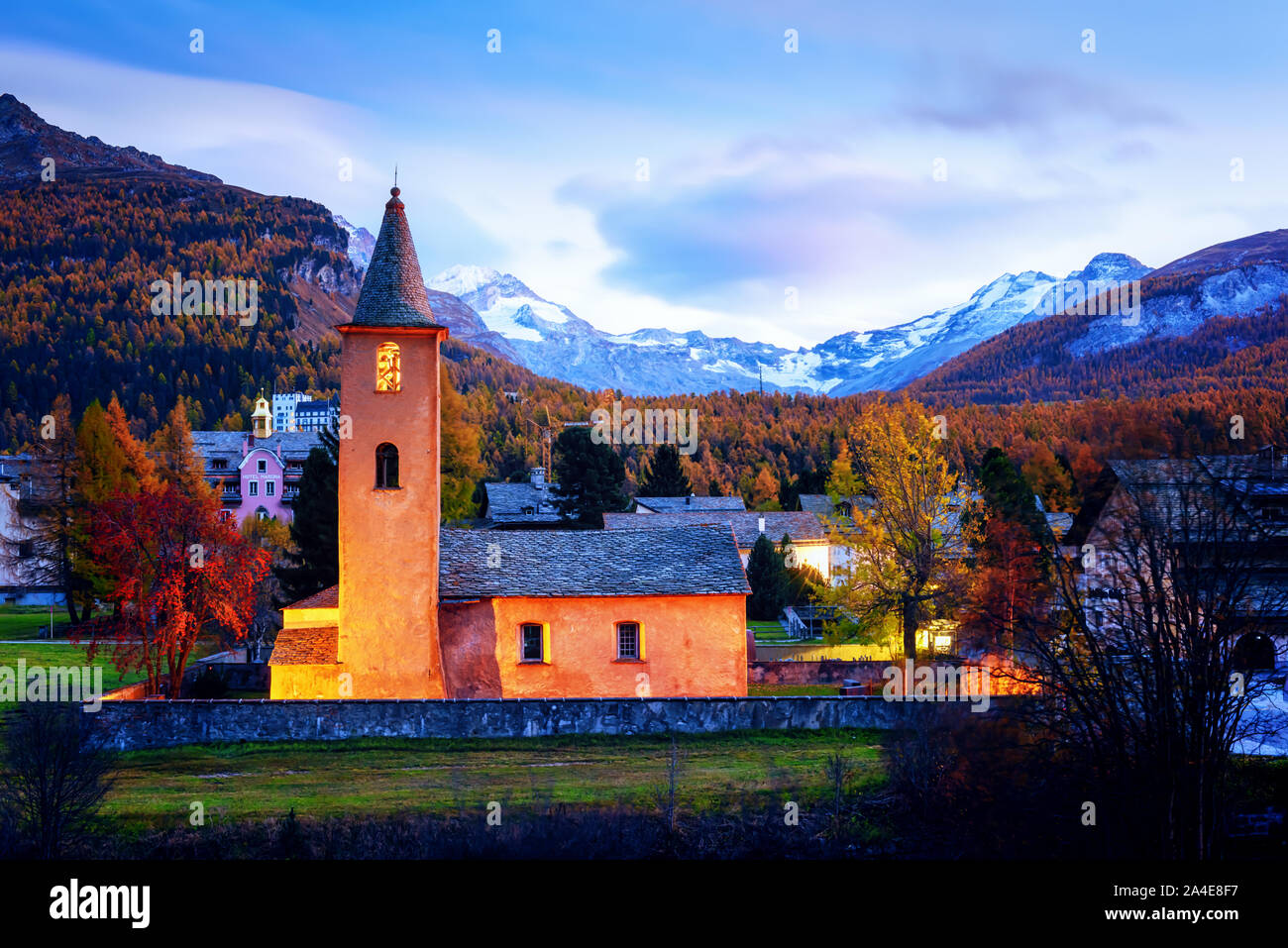 Alte Christentum Kirche in Sils Dorf (in der Nähe von See Sils) in den Schweizer Alpen. Rotes Licht auf Gebäude und die schneebedeckten Berge im Hintergrund. Schweiz, Maloja Region Oberengadin. Landschaftsfotografie Stockfoto