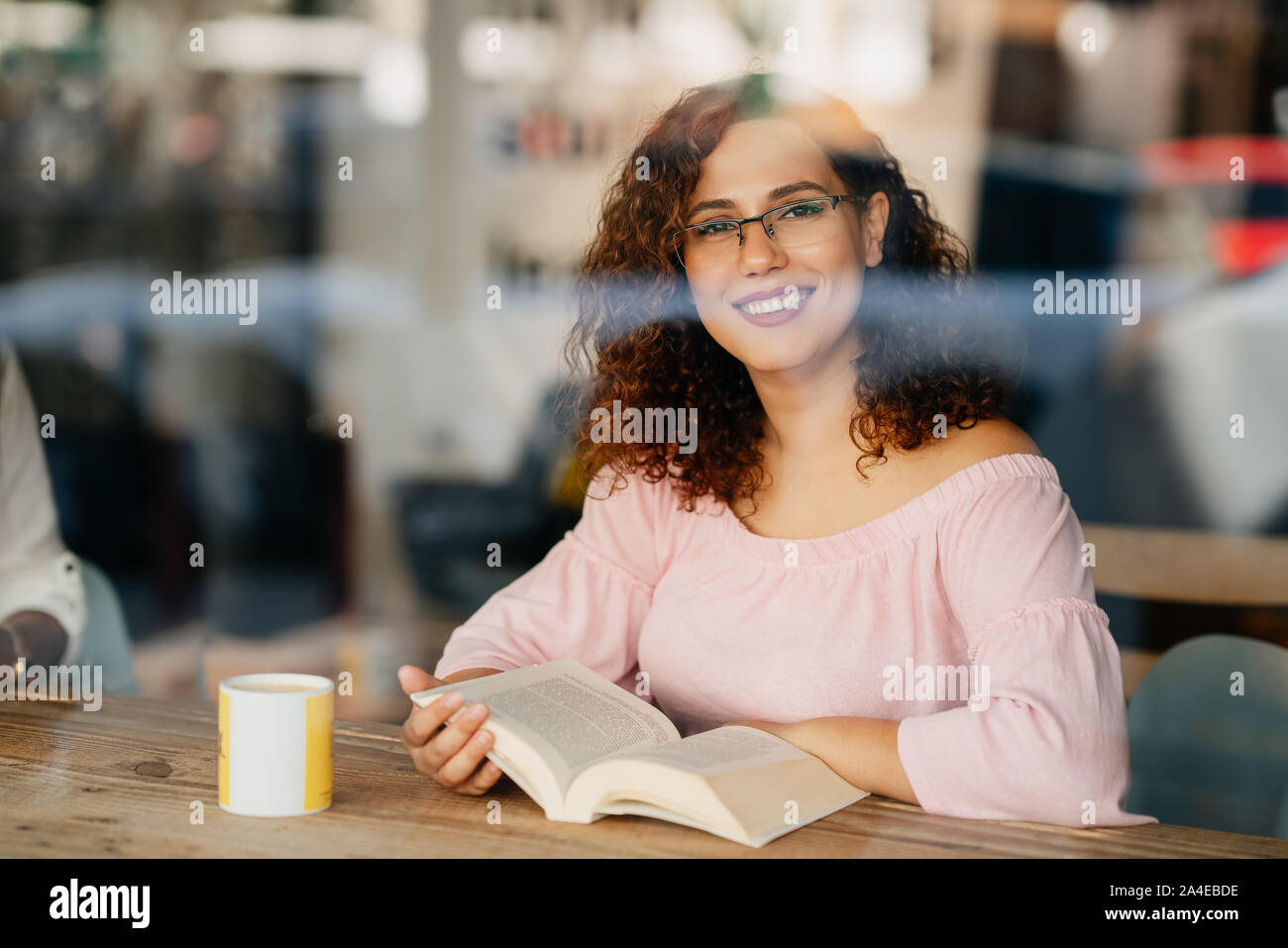 Junge Frau mit Brille Buch lesen im Cafe. Stockfoto