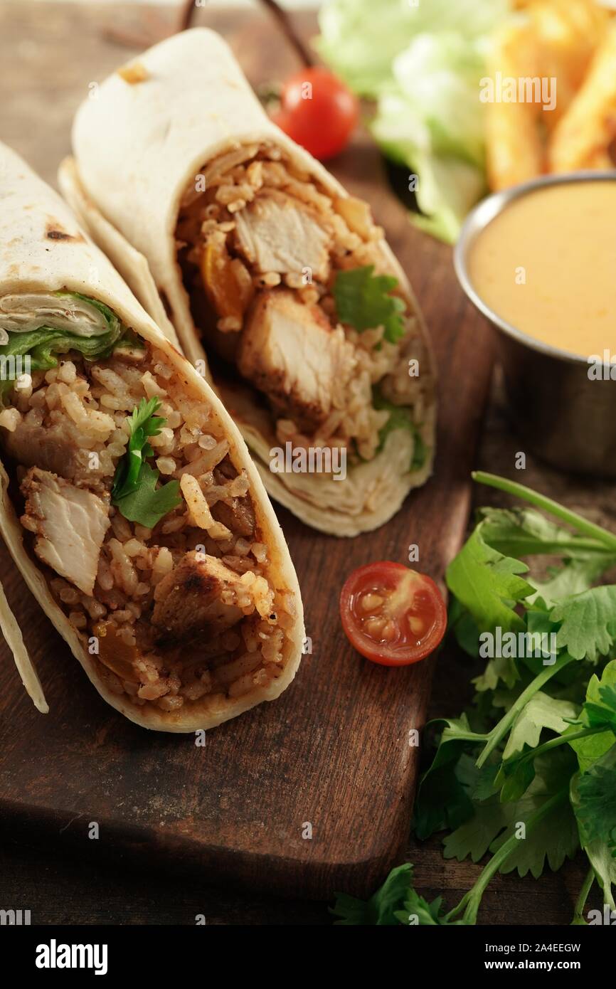 Burritos Wrap mit gegrilltem Hähnchen Reis und Gemüse auf hölzernen Hintergrund, selektiver Fokus Stockfoto