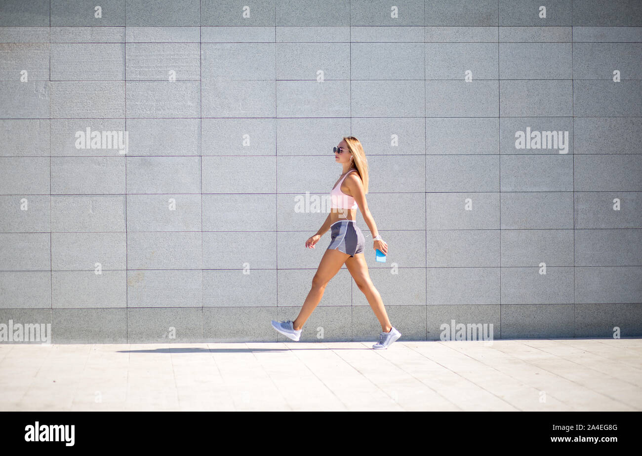Junge Frau mit fit Körper gegen grauen Hintergrund. Weibliche Model in Sportswear Outdoor Aktivitäten. Stockfoto