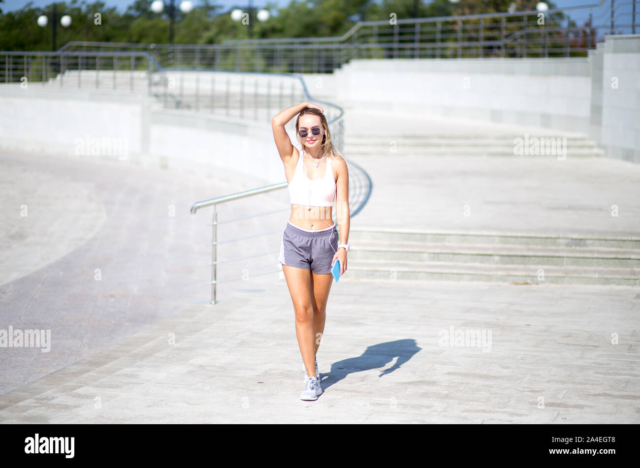 Junge Sportlerin in Shorts und Top Walking im Freien, urbanen Stil. Stockfoto