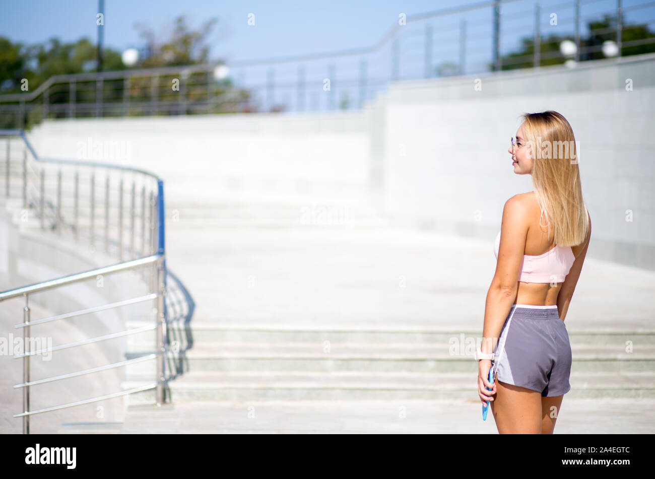 Junge Sportlerin mit ihr bak stehend auf die Kamera zu Fuß im Freien, urbanen Stil. Stockfoto