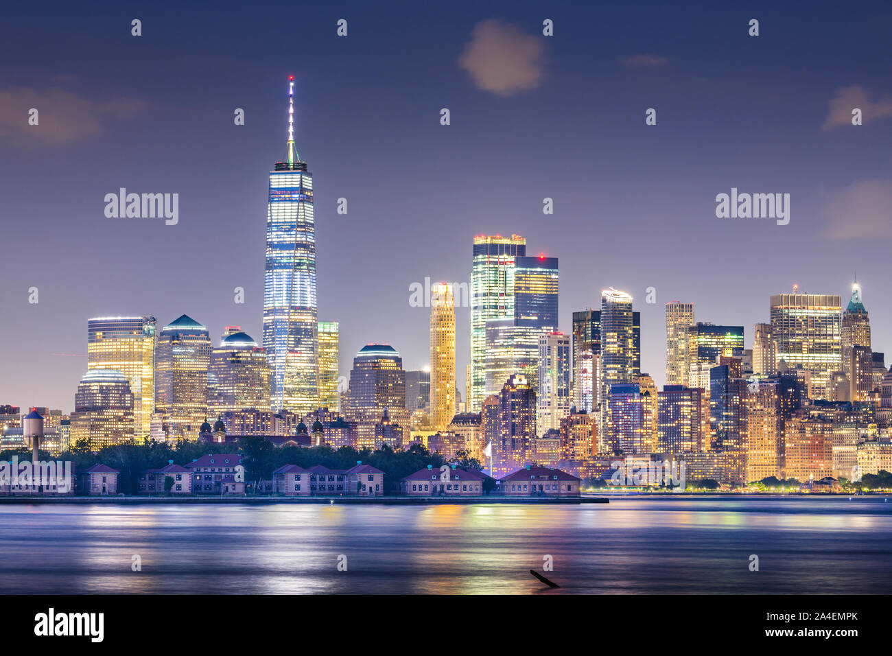 New York, New York, USA Skyline vom Hafen mit Ellis Island in der Nacht. Stockfoto
