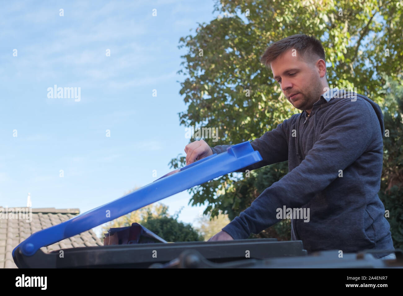 Kaukasische Mann warf ein Papier in einem blauen plastik Müll bin. Stockfoto