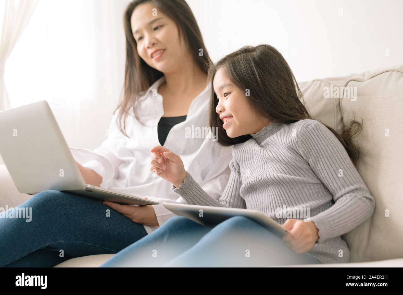 Glückliche Mutter und Tochter mit Laptop- und Tablet-PC Stockfoto