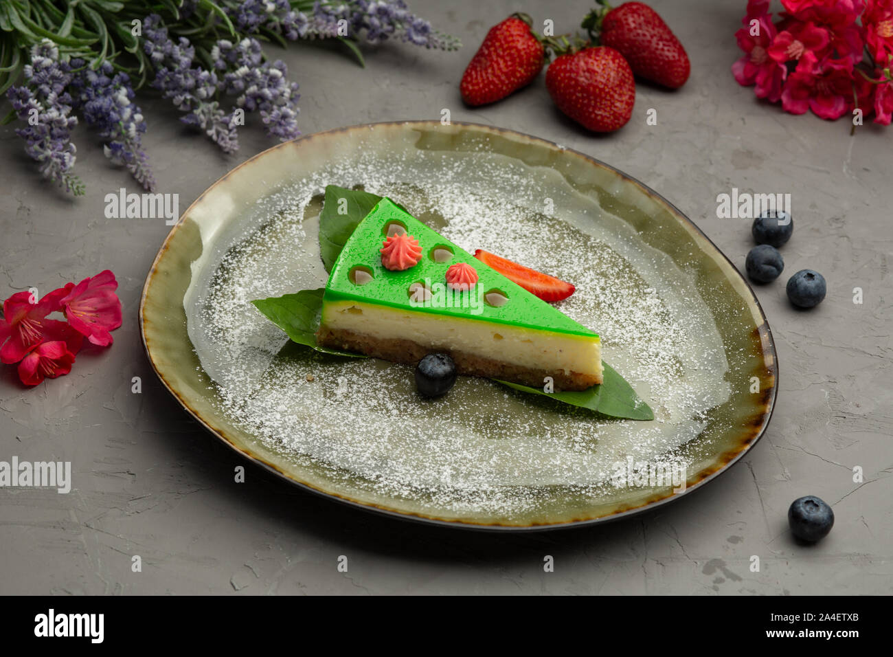 Shortbread Bambus Käsekuchen mit Käse Sahne und frischen Beeren in einer grünen Platte auf grauem Hintergrund Stockfoto