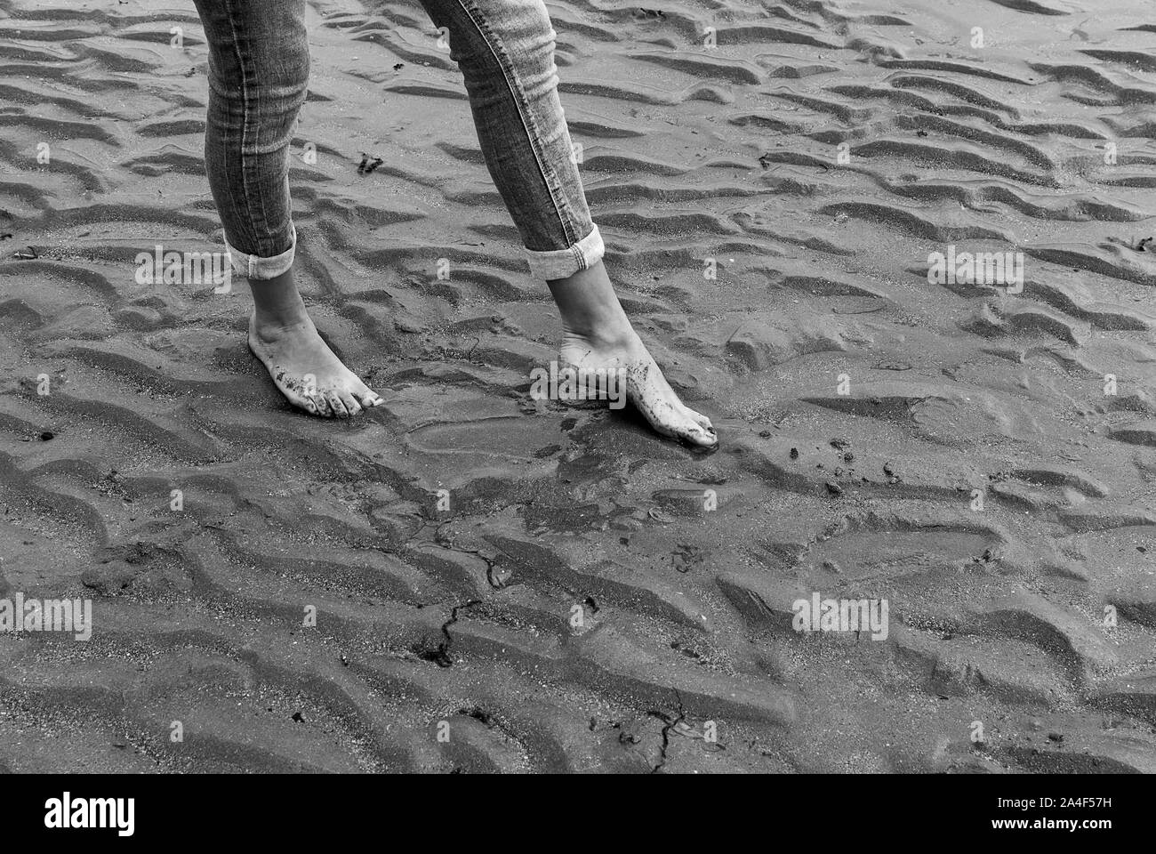 Junge Frau wandern und Spielen auf Sandstrand und hinterlassen Spuren im Strand. Killbrittain, Kilbrittain Strand, Irland. Stockfoto