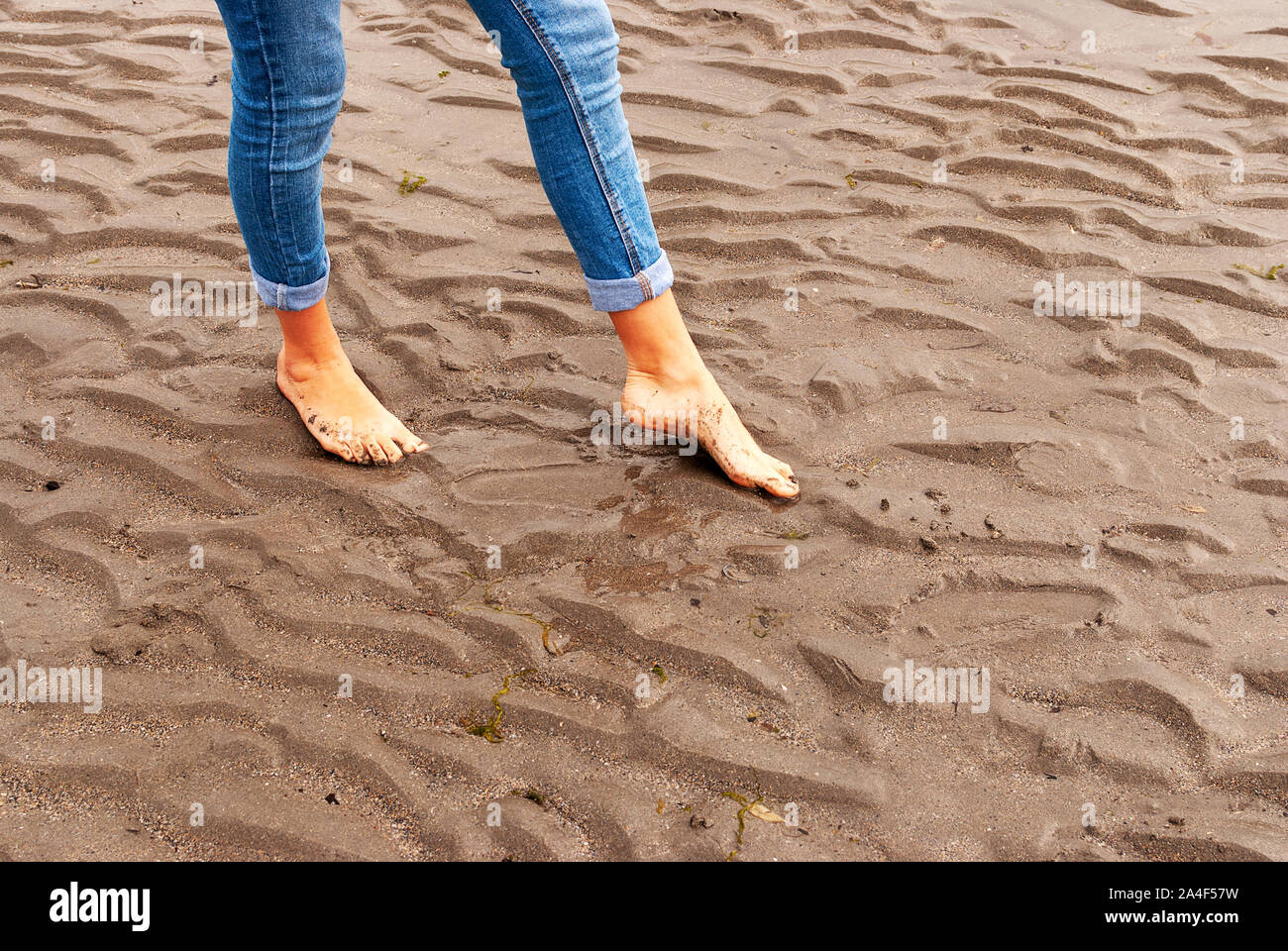 Junge Frau wandern und Spielen auf Sandstrand und hinterlassen Spuren im Strand. Killbrittain, Kilbrittain Strand, Irland. Stockfoto