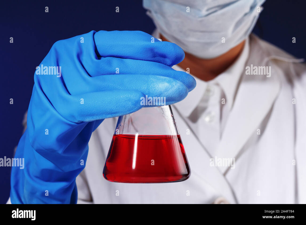 In einem Chemielabor, ein weiblicher Chemiker ist die Analyse eine Flasche mit roter Flüssigkeit. Medizinischen Experiment. Stockfoto