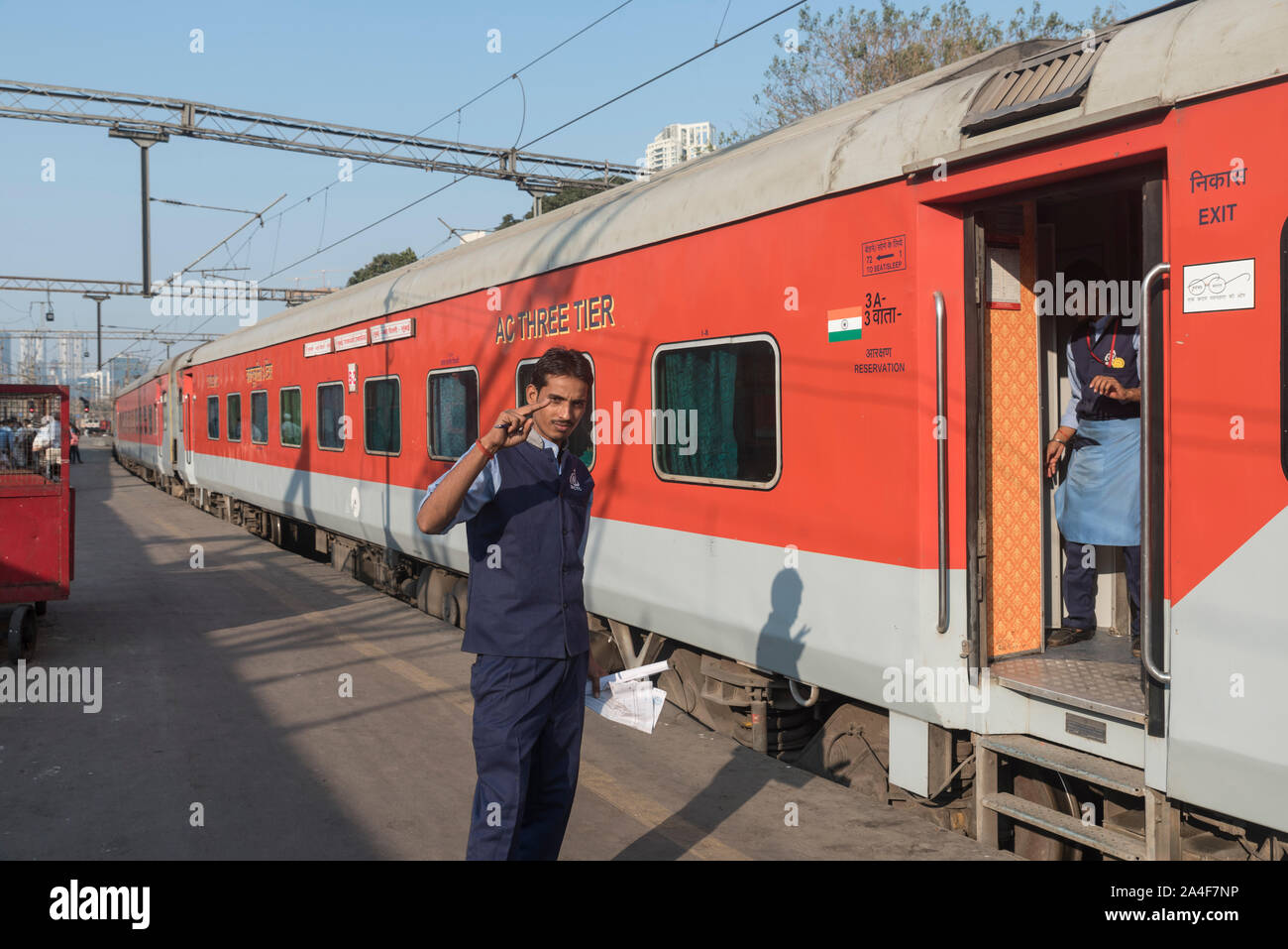 Ein Zug Attendant stellt gegen die Mumbai Rajdhani Express am Hauptbahnhof in Mumbai in Indien. Stockfoto
