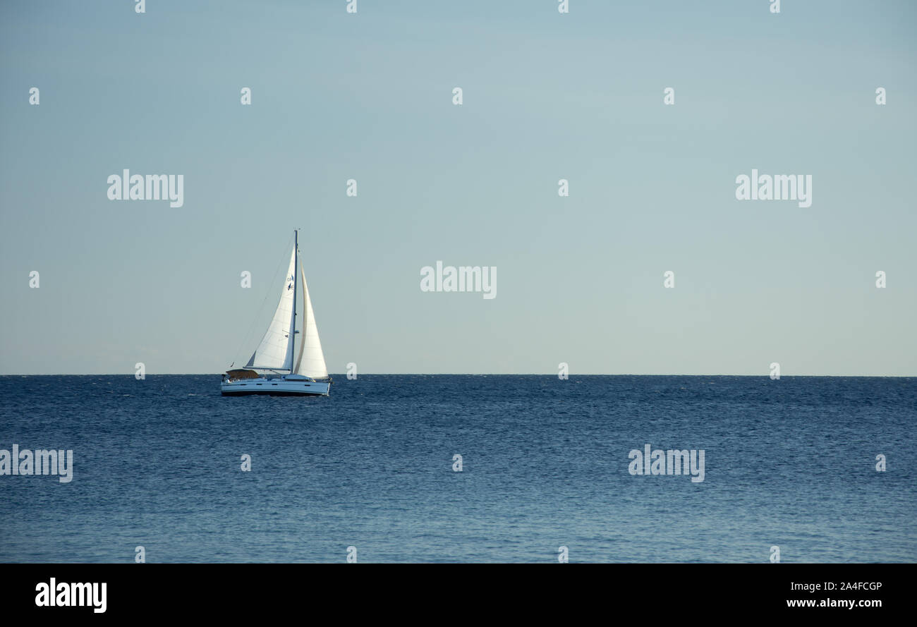 Tag Sommer an der Adria. In der Ferne, ein weißes Segelboot ist Segeln entlang dem Meer in der windigen, sonnigen Tag. Horizontale, Minimalismus Foto. Stockfoto