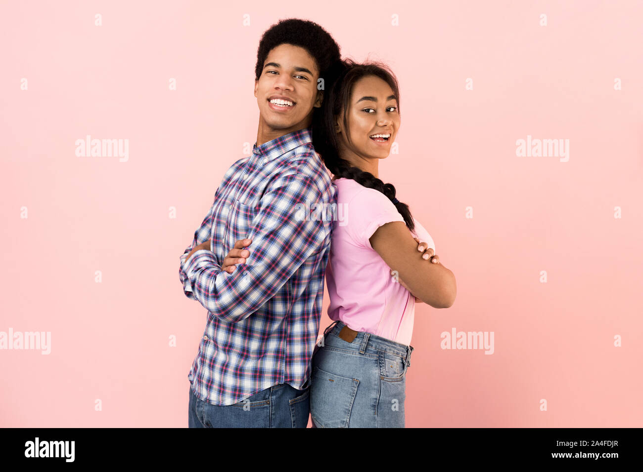 Glückliches junges Paar stehen Rücken an Rücken und lächelnd Stockfoto