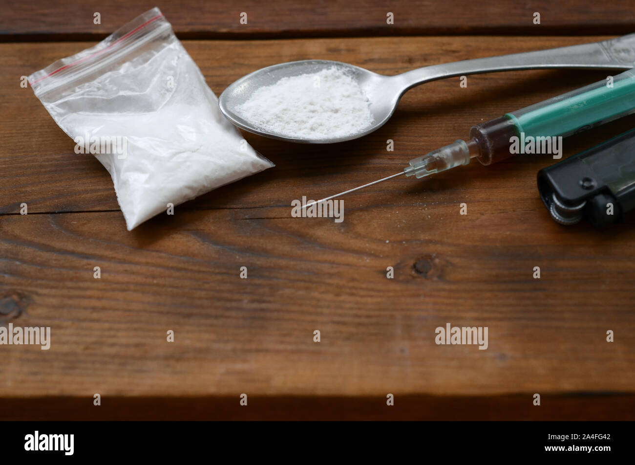 Drogendealer Material. Spritze, leichter und Löffel voll mit weissem Pulver auf Holz- Hintergrund. Heroin und Methamphetamin. Betäubungsmittel sucht Konzept Stockfoto