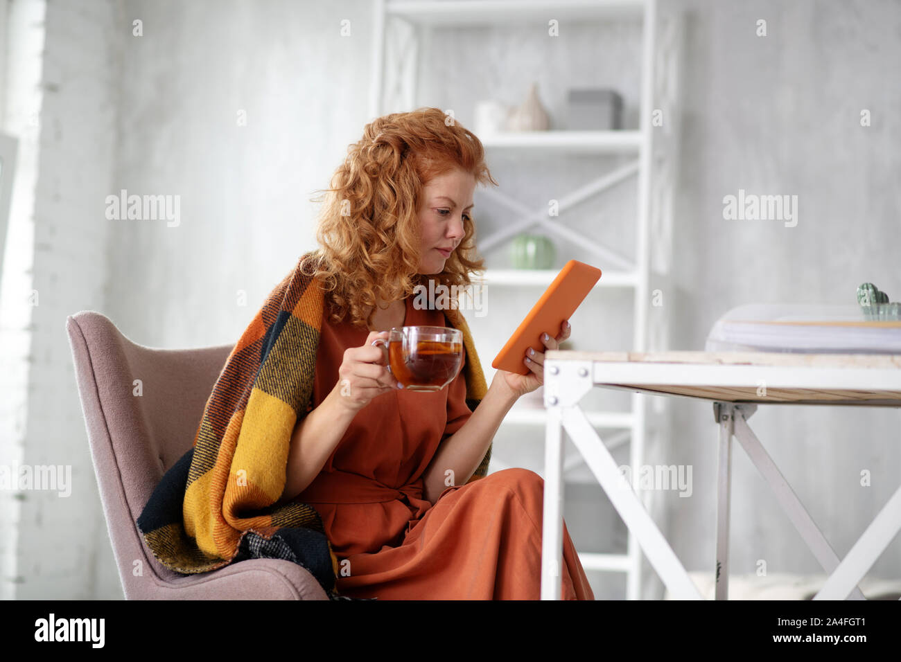Sick Freiberufler Lesen von E-Mails auf Tablet und Tee trinken. Stockfoto
