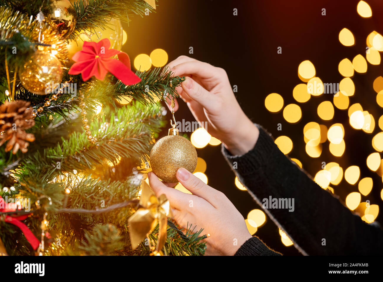 Mädchen schmücken einen Weihnachtsbaum. Closeup Bild der weiblichen Händen verzieren Weihnachtsbaum. Konzentrieren Sie sich auf Ihre linke Hand! Stockfoto