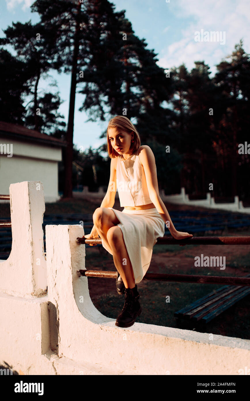 Junge Frau sitzt auf Zaun Stockfoto