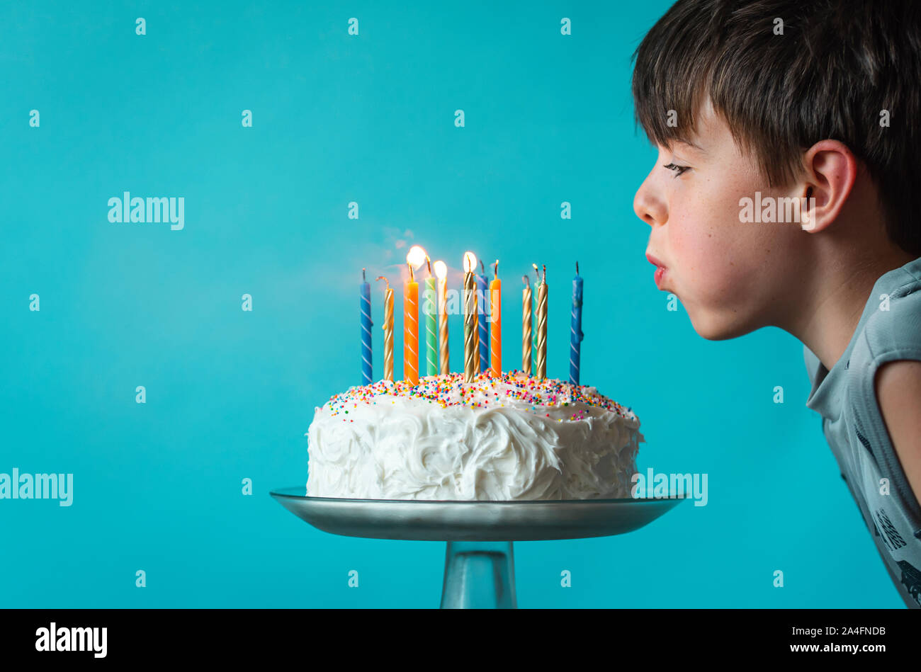 Junge ausblasen Kerzen auf der Geburtstagstorte vor blauem Hintergrund. Stockfoto